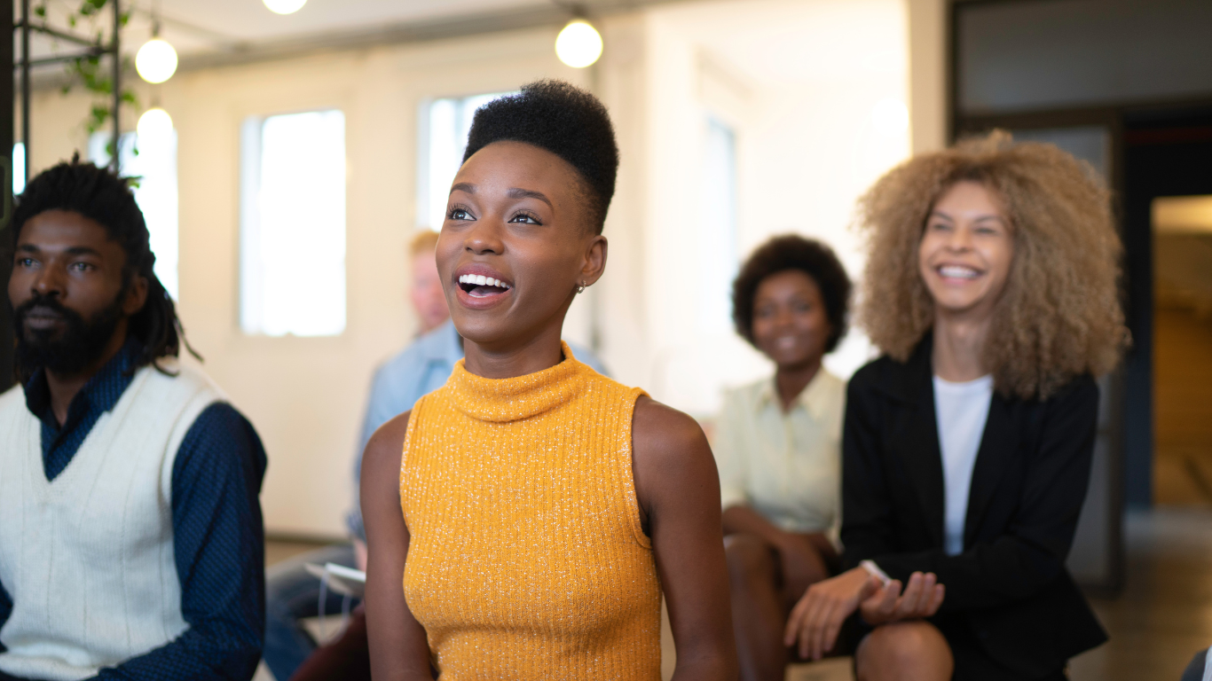 Diverse women of different races sitting together and smiling, representing a fashion brand’s audience.