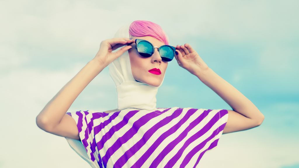 Elegant woman wearing a colorful top, chic sunglasses, and a scarf, exuding bougie sophistication.