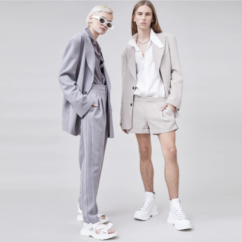 Two women in unisex outfits showcasing gender-neutral fashion trends for 2025.