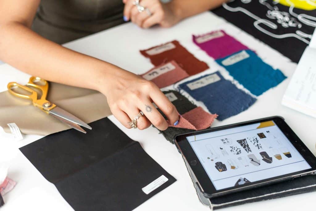 Un créateur de mode sélectionne des échantillons de tissus tout en utilisant une tablette comme référence.