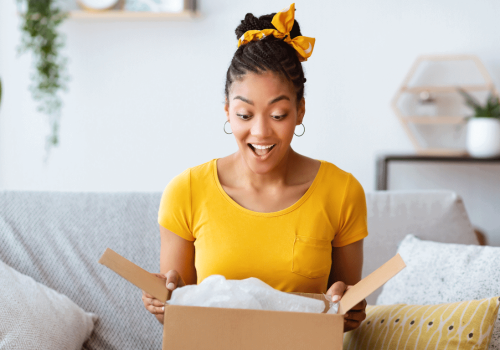 A woman unboxing her winter fashion order, looking happy and excited.