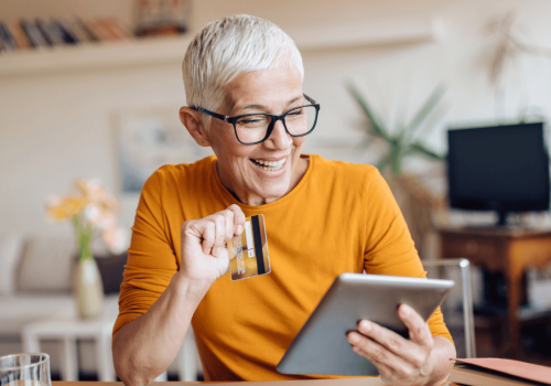 Woman holding a credit card in front of an iPad to make an online clothing purchase
