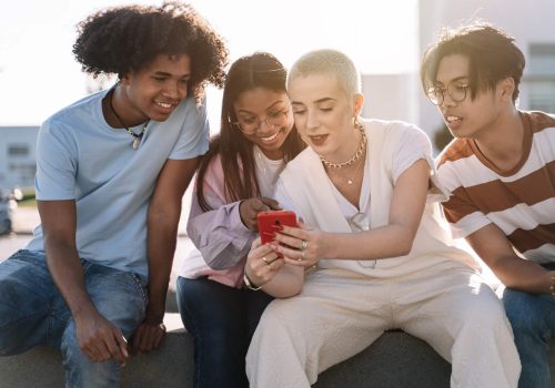 group-of-friends-sitting-together-using-mobile-phones-to-share-content-on-social-media.jpg A bunch of friends checking their smartshope which is an illustration of engagement with social media