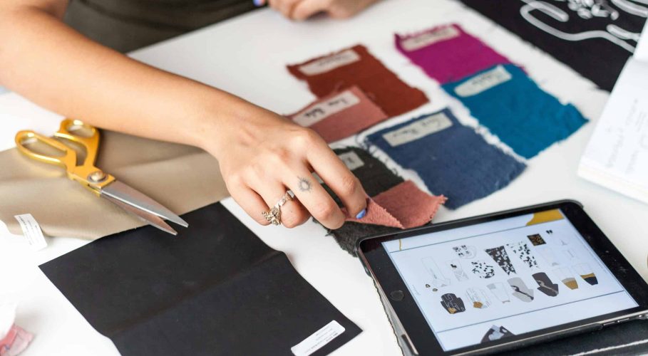 pexels-cristian-rojas-8030145 A fashion designer selecting fabric swatches while using a tablet for design references.